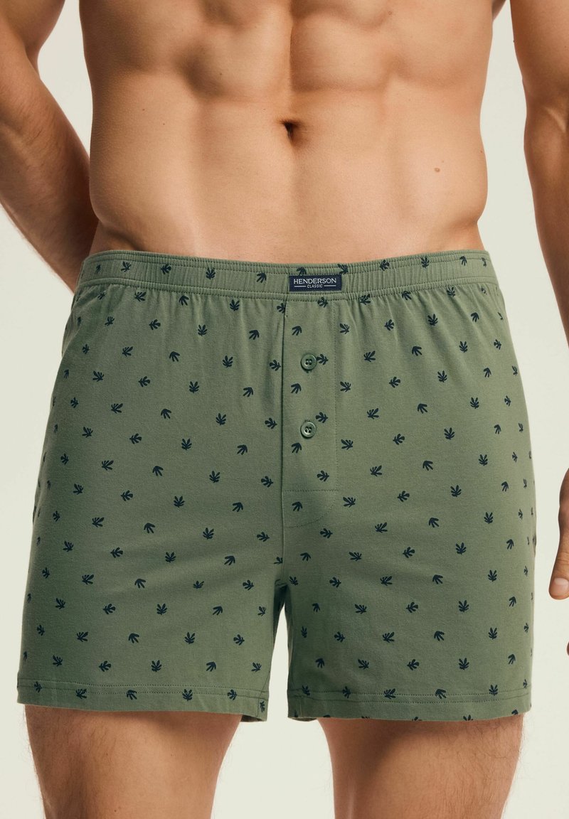 Zielone bawełniane bokserki w liściasty wzór, z guzikowym zapięciem i elastycznym pasem, zapewniające luźny krój i miękką teksturę.