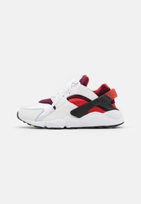 Sneakers met een bovenwerk van wit leer en mesh, rode en zwarte accenten, een gevoerde kraag en een gestructureerde zool voor grip.