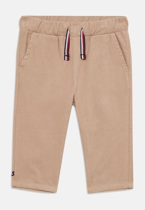 Shorts en velours côtelé beige avec une taille élastique, cordons de serrage ajustables en rouge, blanc et bleu, et deux poches avant.