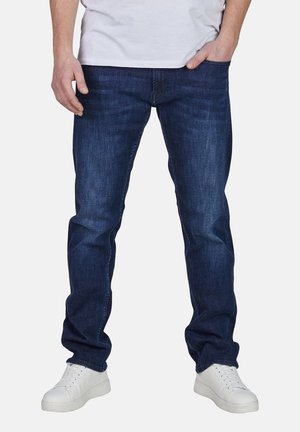 Dark blue denim jeans with a straight-leg cut, featuring visible stitching and a slightly faded texture. Paired with white sneakers.