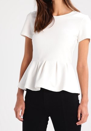 Biała bluzka z krótkim rękawem i baskinką, noszona z czarnymi spodniami, z dopasowanym gorsetem i rozkloszowanymi detalami w talii.