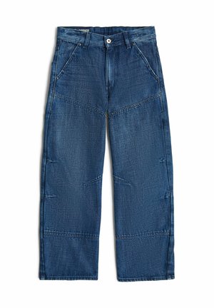 Pantalon de charpentier en denim bleu foncé avec plusieurs détails de coutures, poches avant, passants de ceinture et fermeture par bouton à la taille.