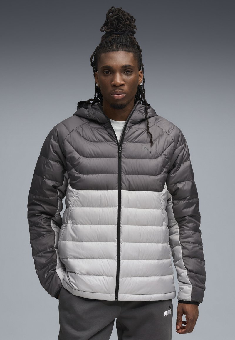 Puffjacke in Grautönen mit horizontalem Steppmuster, ausgestattet mit Kapuze, durchgehendem Reißverschluss und seitlichen Taschen. Weiche, glänzende Textur.