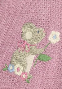 Topolino grigio ricamato con fiocco rosa, che tiene un fiore, su un morbido tessuto a maglia rosa. Presenta accenti floreali in blu, rosa e verde.