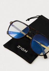 Ochelari rectangulari cu tortoiseshell marron, dotati cu lentile cu nuanță albastră, așezați pe un săculeț negru cu șnur, etichetat "ZIGN."