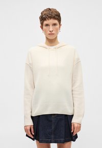 Κρέμα χρώματος φούτερ με κορδόνι, μαλακή υφή και ριμπ μανσέτα, σε συνδυασμό με τζιν φούστα με πτυχώσεις και λεπτομέρειες ραφής.