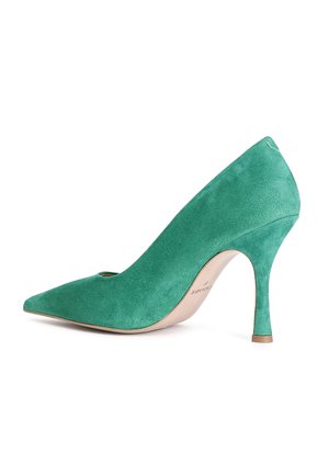 Escarpin vert en daim à talon haut avec une toe pointue et une découpure circulaire sur le côté. Il possède un talon aiguille élancé et une semelle intérieure beige.