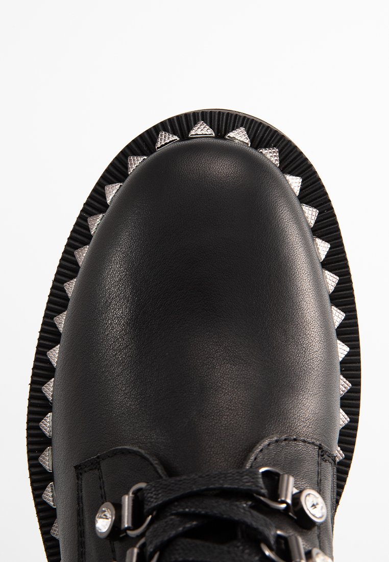 Scarpa in pelle nera con punta rotonda, lati testurizzati, suola rigata nera e argento ben pronunciata e accenti metallici sui lacci e sui lati.