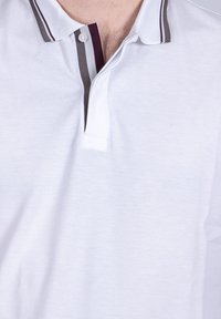 Polo bianco con un'apertura a due bottoni, caratterizzato da un colletto con strisce grigie e borgogna per il dettaglio. Tessuto testurizzato visibile.