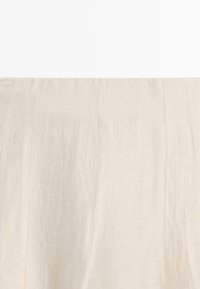 Slonovinově bílá plisovaná lehká tkanina s jemnými vertikálními švy a mírně mačkanou texturou.