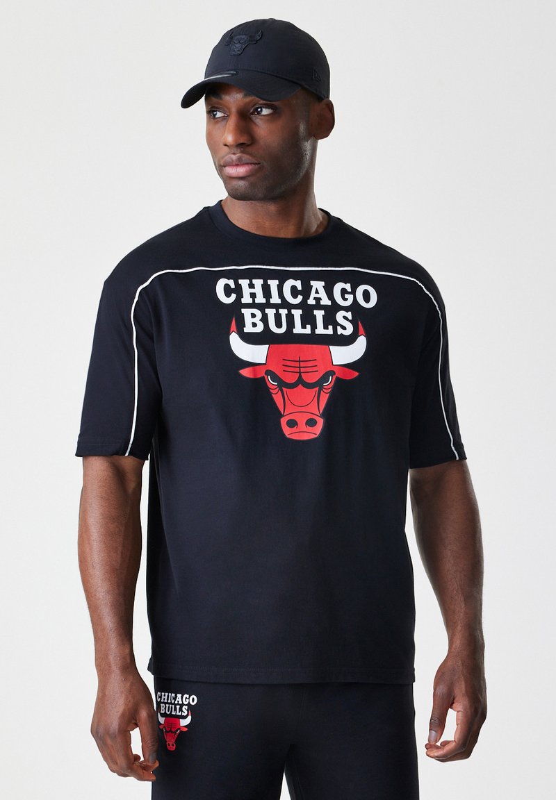 Črna majica s kratkimi rokavi z rdečim logotipom Chicago Bulls in belimi detajli. Nosena z črnimi hlačami, ki prikazujejo sproščen športni slog.