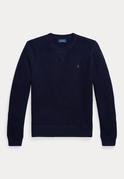 Πλεκτό πουλόβερ σε ναυτικό μπλε με V λαιμόκοψη, ριμπ μανσέτες και τελείωμα. Διαθέτει μικρό λογότυπο στο αριστερό μέρος του στήθους. Υφασμένο ύφασμα για ζεστασιά.