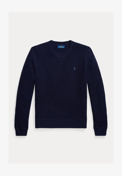 Πλεκτό πουλόβερ σε ναυτικό μπλε με V λαιμόκοψη, ριμπ μανσέτες και τελείωμα. Διαθέτει μικρό λογότυπο στο αριστερό μέρος του στήθους. Υφασμένο ύφασμα για ζεστασιά.