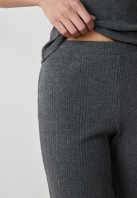 Grijze geribde gebreide broek met een comfortabele tailleband, met de nadruk op textuur en patroon. De close-up richt zich op de stof en de pasvorm.