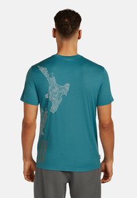 Turkoosi lyhythihainen t-paita, jossa on takana valkoinen kontuurikartta maan pinnasta sekä pieni oranssi yksityiskohta alhaalla.