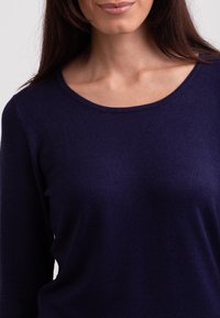 Navy blue sweter z okrągłym dekoltem i długimi rękawami, wykonany z miękkiej, teksturowanej dzianiny, bez widocznych wzorów czy elementów metalowych.