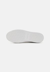 White rubber sole with a textured pattern featuring the brand name "Calvin Klein" and circular designs throughout. Flat and smooth finish.