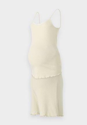 Σαλοπέτα εγκυμοσύνης σε ανοιχτό κίτρινο χρώμα με υφή, κοφτές άκρες, ρυθμιζόμενους ιμάντες και εφαρμοστή σχεδίαση.