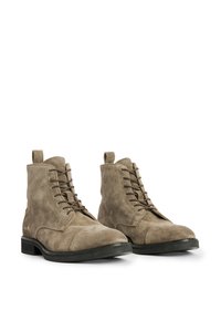 Stivaletti in suede marrone chiaro con lacci, punta arrotondata, suola piatta in gomma nera e linguette per indossarli facilmente.