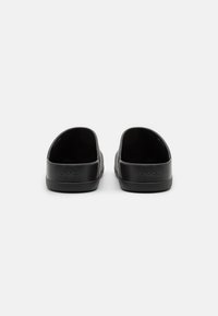 Scarpe slip-on nere con una parte superiore grigia testurizzata, caratterizzate da una suola e un retro in gomma nera liscia, design aperto per una facile vestibilità.