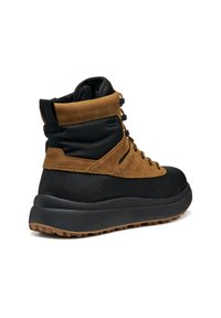Botas de caña alta con parte superior de ante marrón y acentos de tela negra, que cuentan con cordones negros, una suela de goma texturizada y un cuello acolchado.