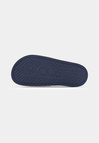 Lacoste sko sål i marineblå gummi med en tekstureret overflade og diagonale riller; har præget brandlogo "LACOSTE."