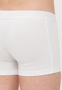 Shorts en coton blancs avec une texture lisse et une taille élastique, présentant un design simple sans motifs ni accents visibles.