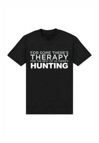 Černé bavlněné tričko s tučným bílým textem: "PRO NĚKOHO EXISTUJE TERAPIE, PRO NÁS OSTATNÍ EXISTUJE LOV." Krátké rukávy, kulatý výstřih.