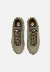 Olivgröna sneakers med mesh-överkonstruktion, texturerat mönster, vadderad tunga och rund logotypdetalj. Utrustad med snörning och vadderad sula.