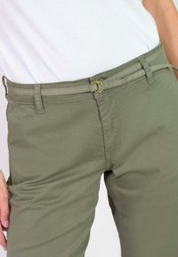 Olijfgroene katoenen broek met een vlakke voorkant, voorzien van een riem met een gouden ring en vijf riemlussen. Gladde textuur, casual pasvorm.