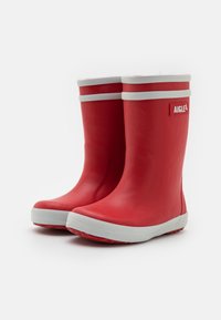 Bottes de pluie en caoutchouc rouge avec des accents blancs et une semelle texturée, présentant un design à bout arrondi et un logo sur le côté.