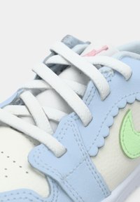 Ανοιχτό μπλε αθλητικό παπούτσι με λευκές και ανοιχτοπράσινες λεπτομέρειες, που διαθέτει λείο δέρμα, υφασμάτινες λεπτομέρειες και επίπεδα λευκά κορδόνια.