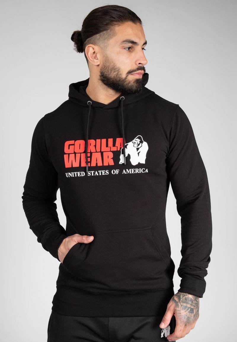 Hoodie noir avec cordons de serrage, affichant un audacieux graphique rouge et blanc "GORILLA WEAR" et "ÉTATS-UNIS D'AMÉRIQUE" à l'avant. Texture lisse.