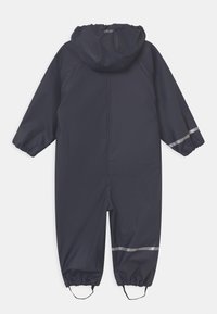 Granatowy wodoodporny kombinezon z kapturem, elastycznymi mankietami i odblaskowymi paskami na nogach; gładka tekstura i projekt zapewniający pełne pokrycie ciała.