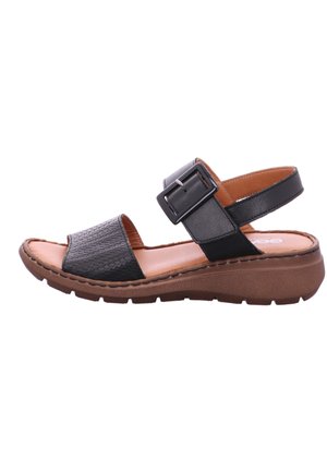 Schwarze Ledersandale mit einem strukturierten, gewebten Riemen und einer breiten, verstellbaren Schnalle. Braune Gummisohle und gepolsterte Innensohle für Komfort.