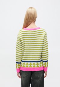 Pruhovaný pletený sveter v zelenej a bielej farbe, s ružovým golierom a lemom. Na spodnej časti má geometrický vzor trojuholníkov v modrej a žltej farbe.