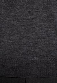 Gros plan sur un tissu tricoté gris foncé avec une texture subtile et un ourlet côtelé en bas.
