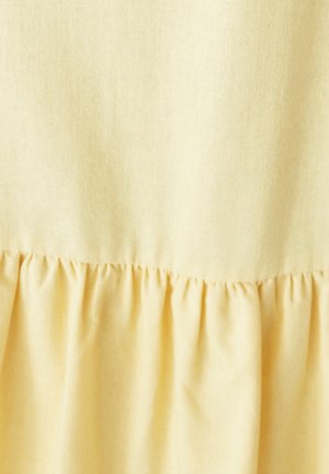 Light yellow fabric with a smooth texture, featuring a gathered hemline that adds dimension to the overall design.
