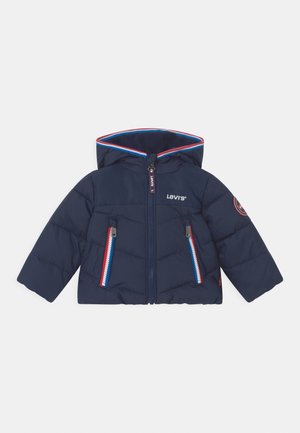 Granatowa pikowana kurtka z kapturem, z czerwonym i niebieskim wykończeniem, kieszeniami na zamek i zamkiem błyskawicznym z przodu. Logo na klatce piersiowej i ramieniu.