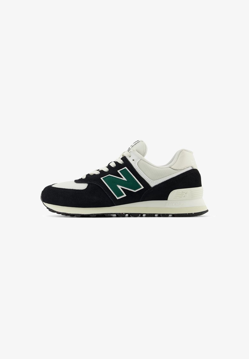 Baskets New Balance noir et blanc avec logo "N" vert, lacets blancs, tige en mesh et semelle rembourrée sur un fond blanc.
