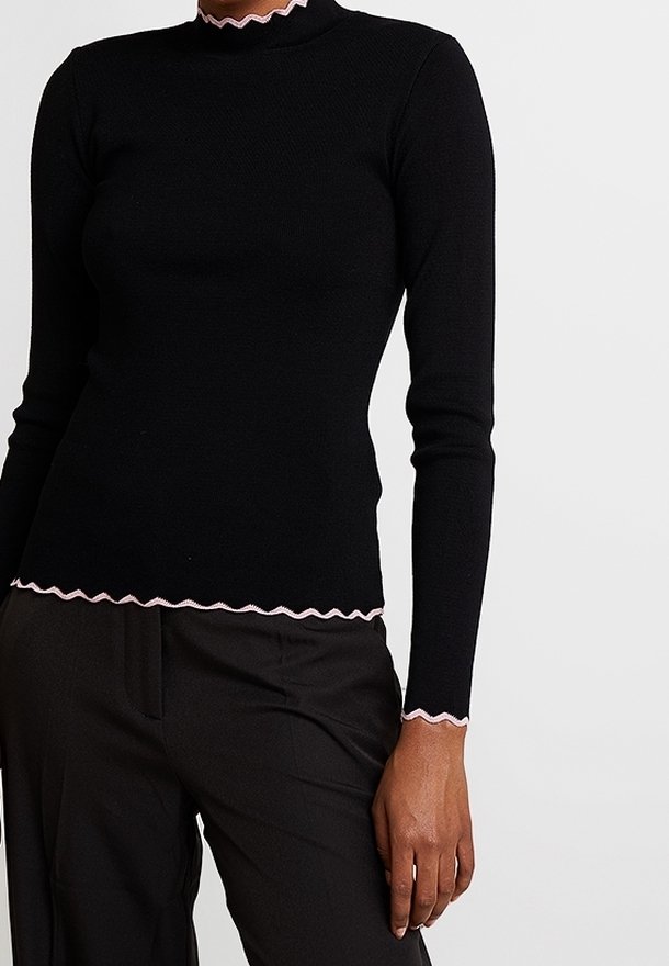 Černý top s dlouhým rukávem a přiléhavým střihem, s růžovou ozdobnou volánovou lemovkou podél výstřihu a spodního lemu. Vyrobený z �žebrované látky.