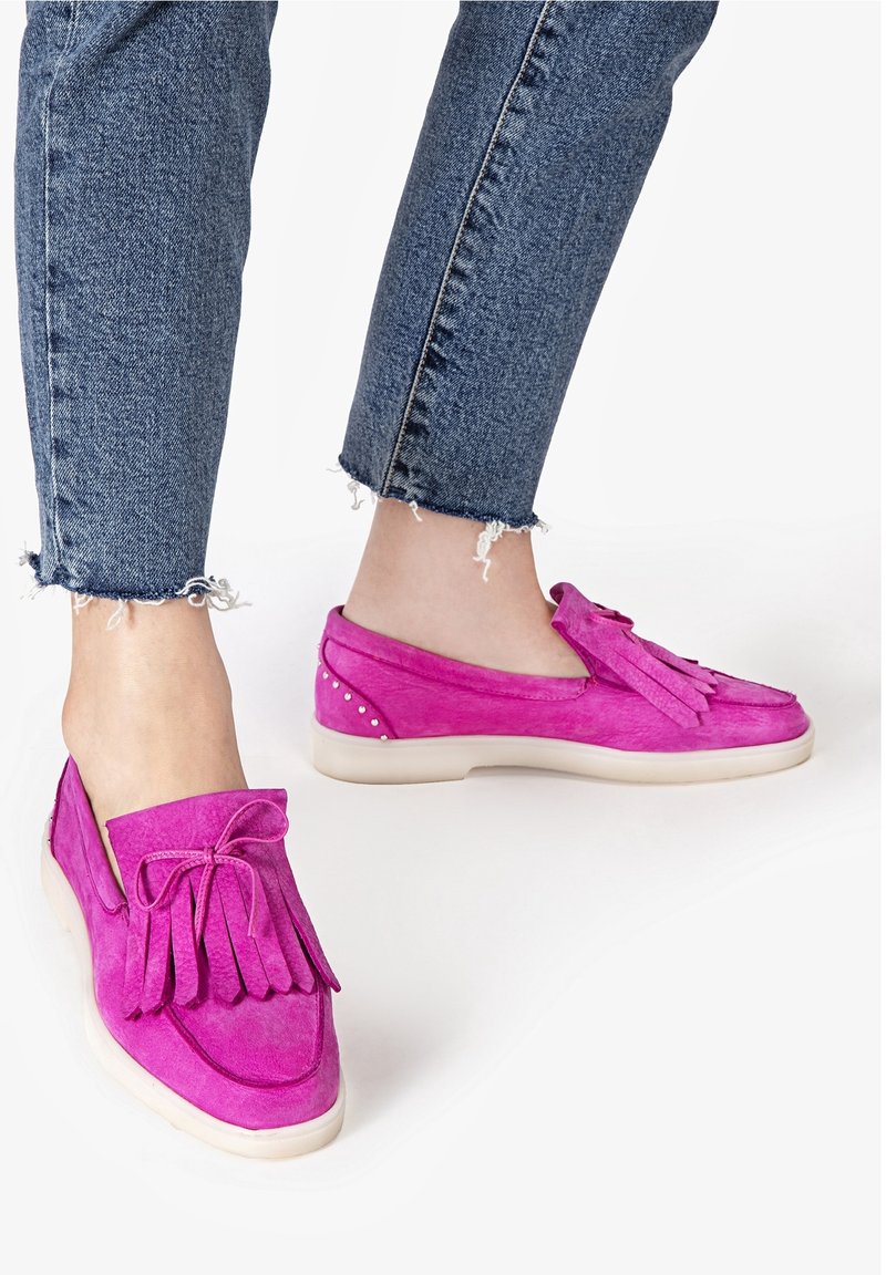 Fuchsiasuede slip-on skor med fransar och en båt, med en vit gummisula och dekorativa nitar på hälen. Bärs med avkortade jeans.