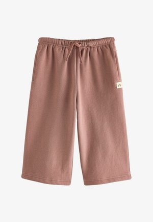 Braune knielange Shorts aus weichem Stoff mit elastischem Bund, Kordelzug, Seitentaschen und einem kleinen Etikett mit Regenbogenlogo am rechten Bein.
