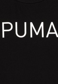 Juodas marškinėliai su dideliu, ryškiu baltu "PUMA" logotipu krūtinės srityje. Medžiaga atrodo lygi su šiek tiek blizgesio.