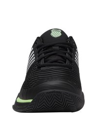 Încălțăminte sport neagră cu panouri de plasă cu model, partea superioară texturată și un accent verde pe talpă; dispune de șireturi și logo pe limbă.