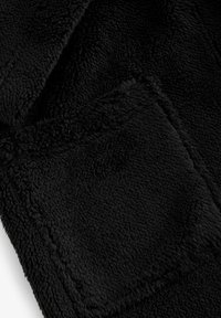 Schwarze Fleece-Decke mit einer weichen, strukturierten Oberfläche. Verfügt über ein dezentes Taschendetail und gesäumte Kanten. Ideal für Wärme und Komfort.