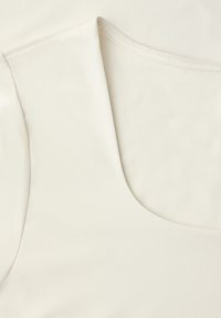 Zbliżenie na biały, bezrękawnik pokazujący gładką teksturę tkaniny oraz czyste, zaokrąglone szwy przy dekolcie.