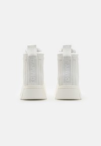 Białe wysokie sneakersy wykonane z gładkiego materiału, z płaską podeszwą i z logo wytłoczonym na pętelkach z tyłu. Minimalistyczny design.