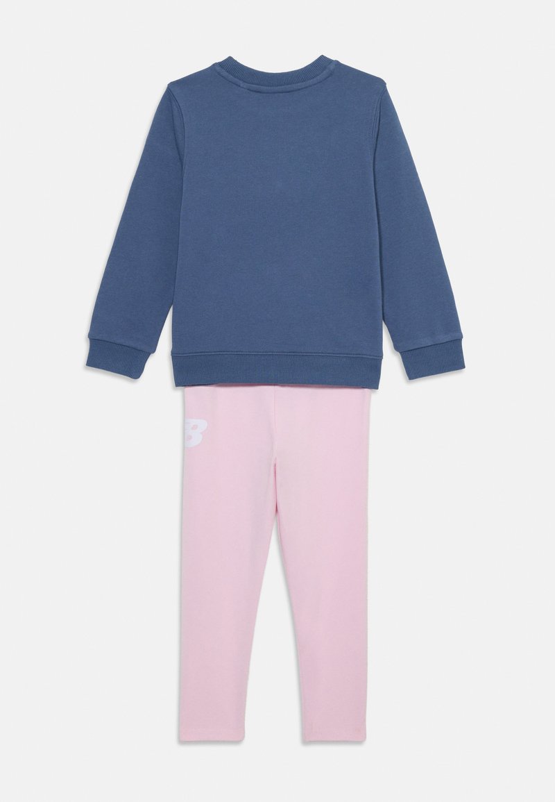 Sweatshirt en coton bleu foncé à manches longues et col rond, associé à un legging rose clair avec un logo blanc sur la hanche.