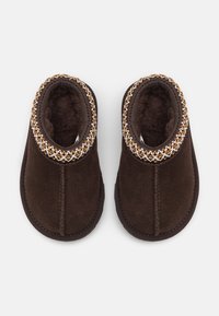 Chaussons en feutre marron avec une doublure douce et une bordure décorative tressée en or et blanc au col. Bout arrondi et semelle flexible.